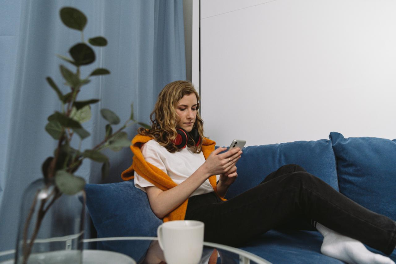 person scrolling booking websites on phone couch